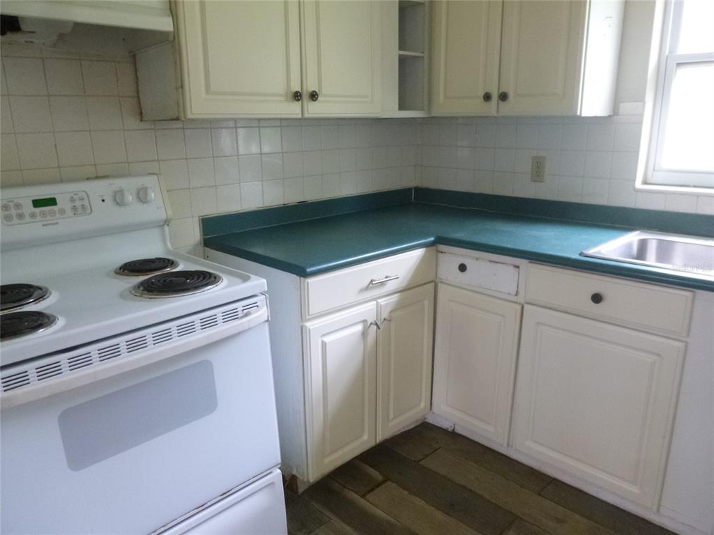 A kitchen features white cabinets, a green laminate countertop, a white stove, and tiled walls — 12 HWY 630 W, FROSTPROOF, FL