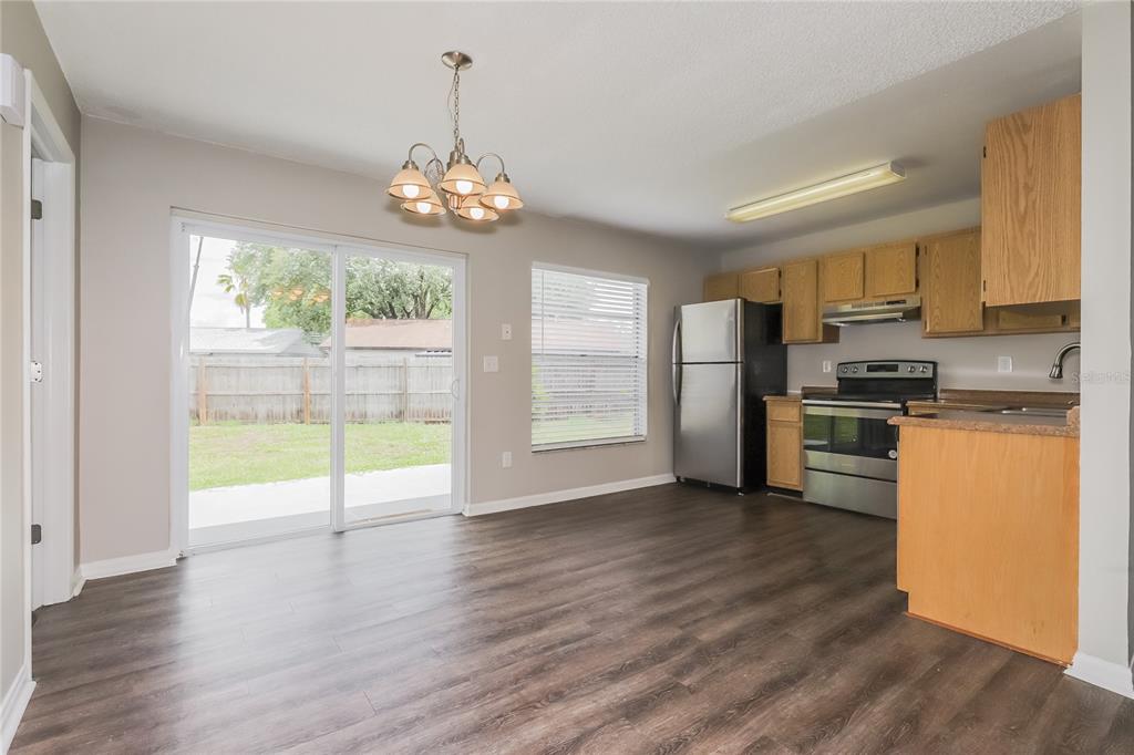 A kitchen and dining area with wood-look flooring, light-colored walls, and a sliding glass door — 1002 PINEHAVEN COURT, BRANDON, FL