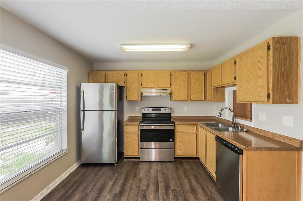 A kitchen with wood cabinets, stainless steel appliances, and dark wood-look flooring — 1002 PINEHAVEN COURT, BRANDON, FL