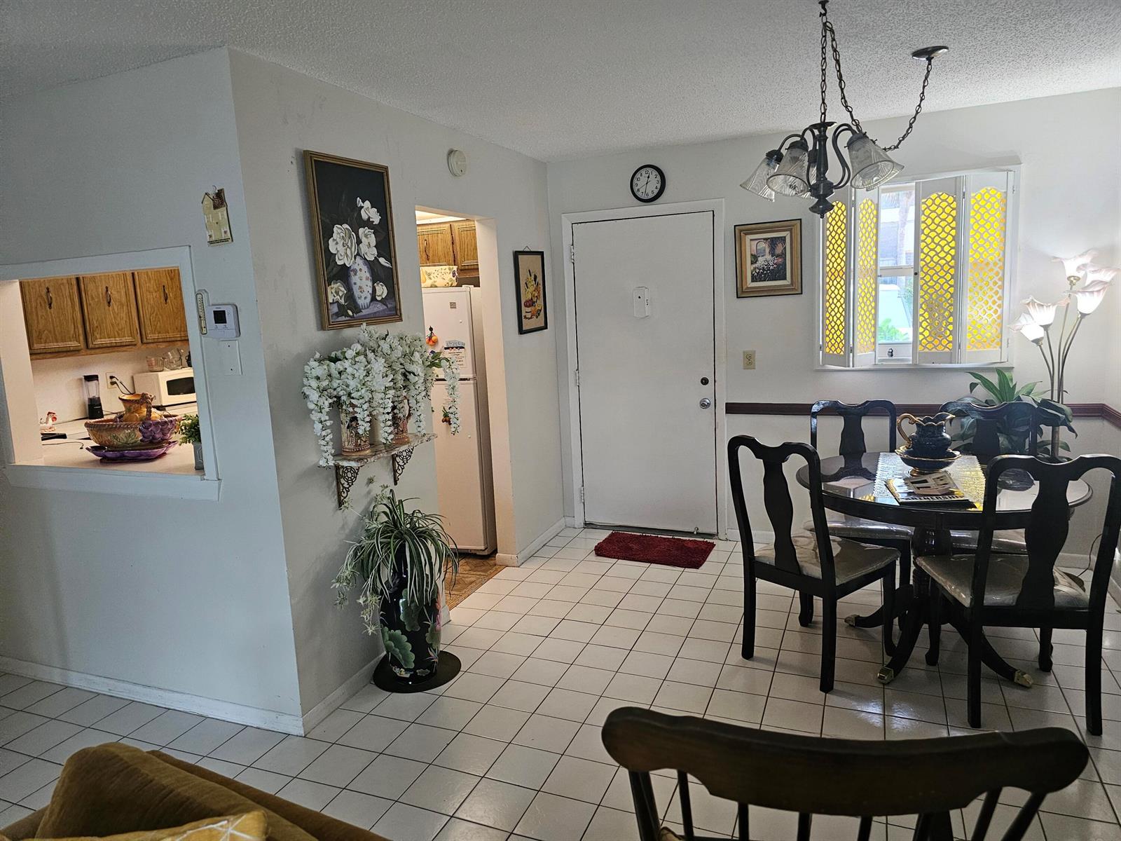 A dining area with a round table, tile flooring, and an open view into the kitchen — 721 Lori Dr # 105, Palm Springs FL 33461, PALM SPRINGS, FL