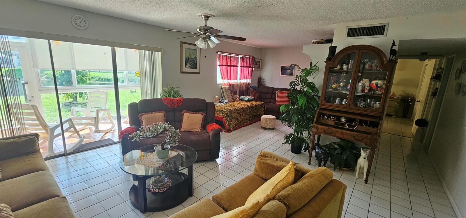 A living room with tile floors, a ceiling fan, and a sliding glass door view — 721 Lori Dr # 105, Palm Springs FL 33461, PALM SPRINGS, FL