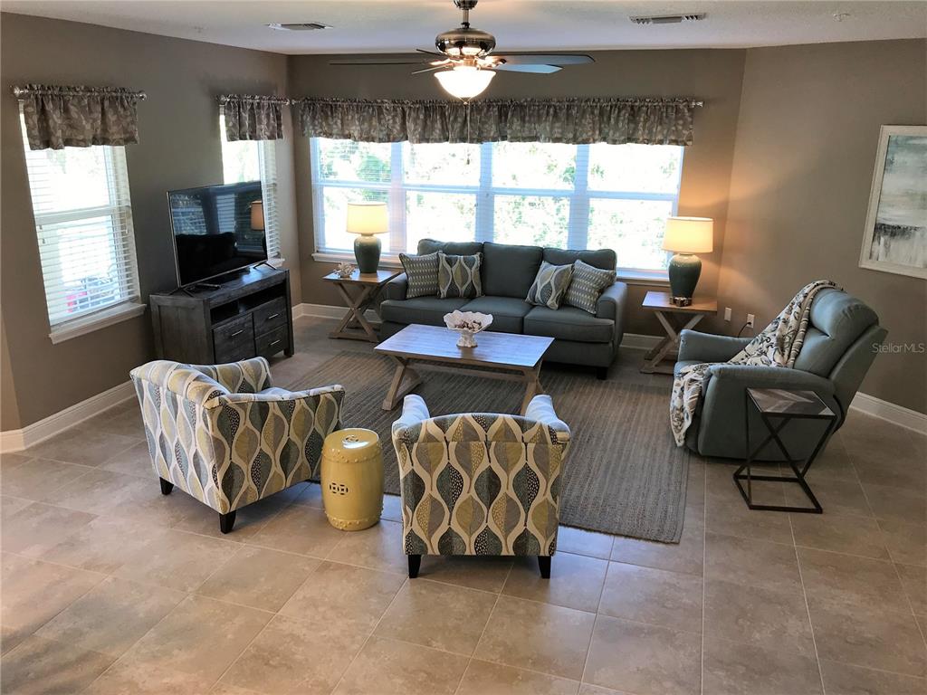 A living room features a sofa, two patterned armchairs, a recliner, and tile flooring — 7730 34TH AVENUE W UNIT 101, BRADENTON, FL