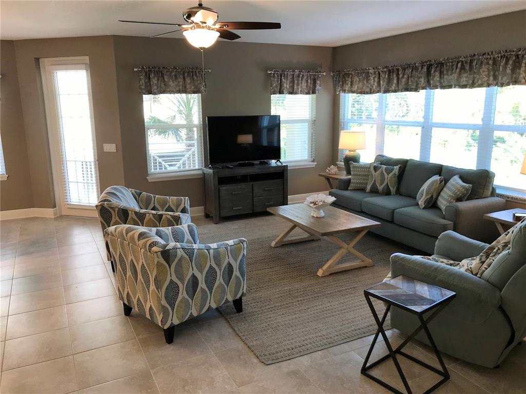 A living room features tile floors, a ceiling fan, a sofa, and patterned armchairs — 7730 34TH AVENUE W UNIT 101, BRADENTON, FL