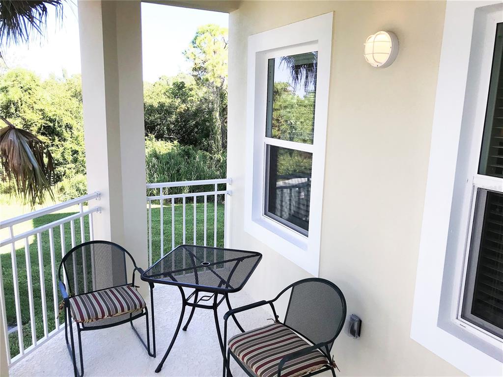 A covered balcony features a small metal table and two chairs with striped cushions — 7730 34TH AVENUE W UNIT 101, BRADENTON, FL