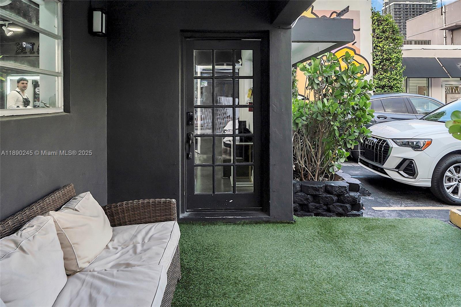 A patio area features a wicker sofa, artificial grass, and a glass-paned door — 2700 Biscayne Blvd, Miami FL 33137, MIAMI, FL