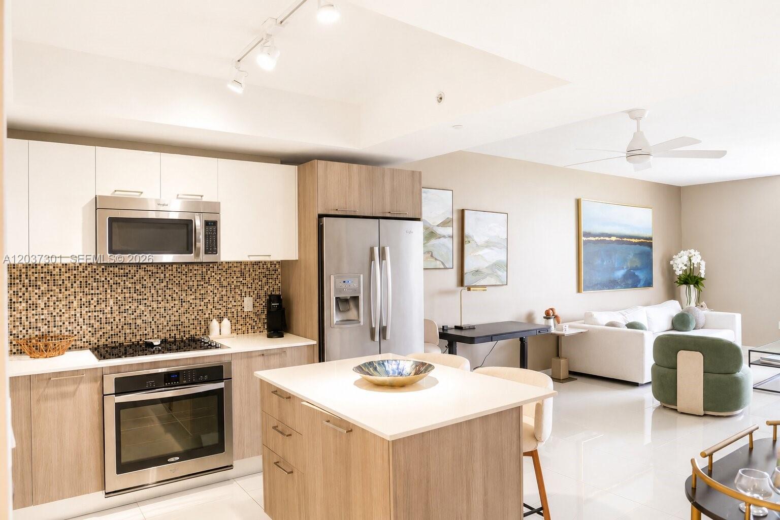 A modern kitchen with light wood cabinets, stainless steel appliances, and an island with seating — 5300 Paseo Blvd # 1510, Doral FL 33166, DORAL, FL