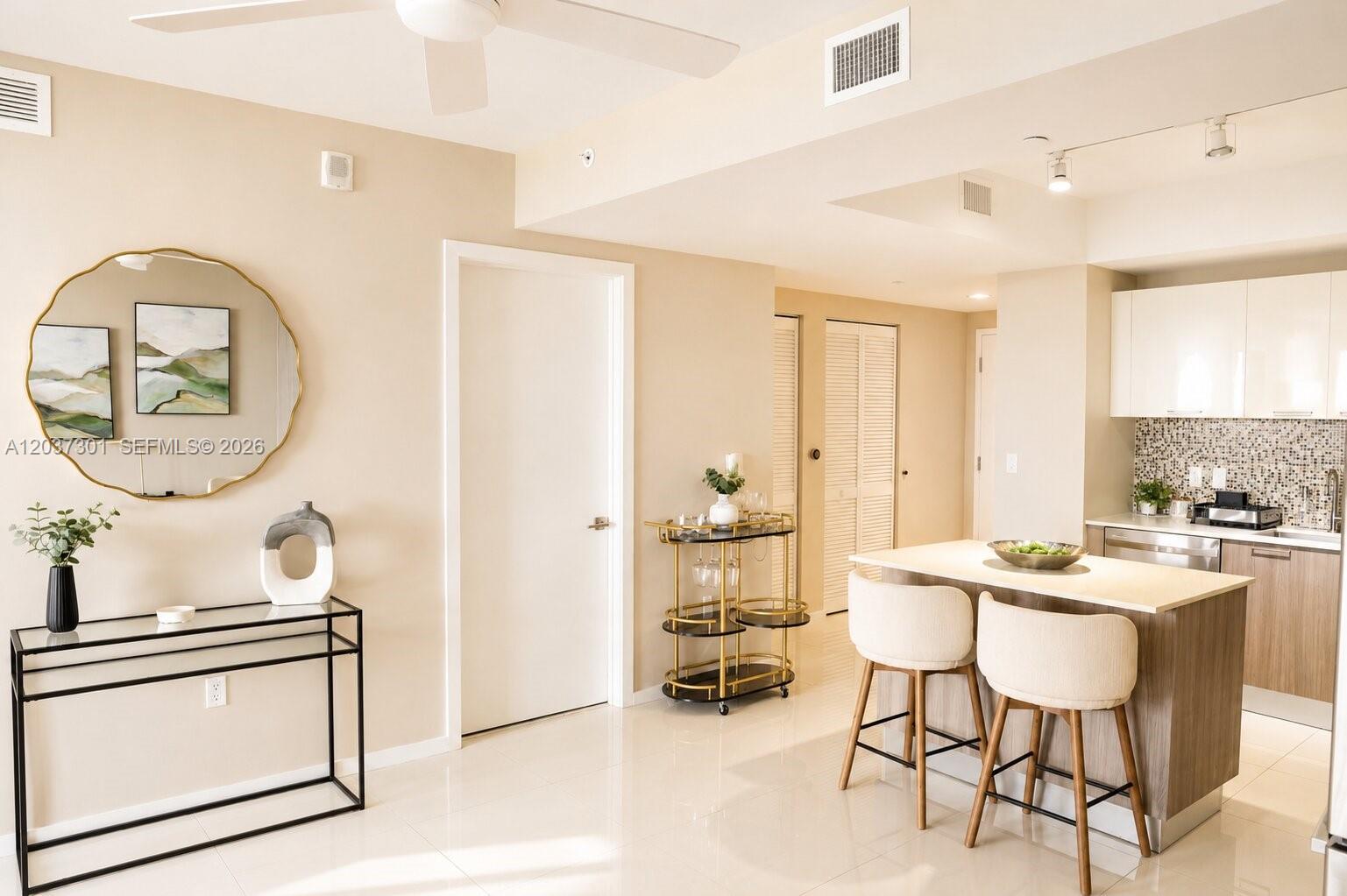 A kitchen with a breakfast bar and stools sits adjacent to a dining area — 5300 Paseo Blvd # 1510, Doral FL 33166, DORAL, FL