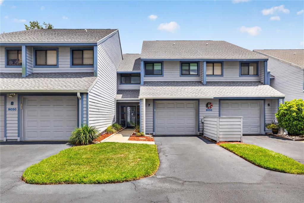 A multi-unit residential building with gray siding, shingled roofs, and attached garages — 9050 PARK BOULEVARD UNIT 7, SEMINOLE, FL