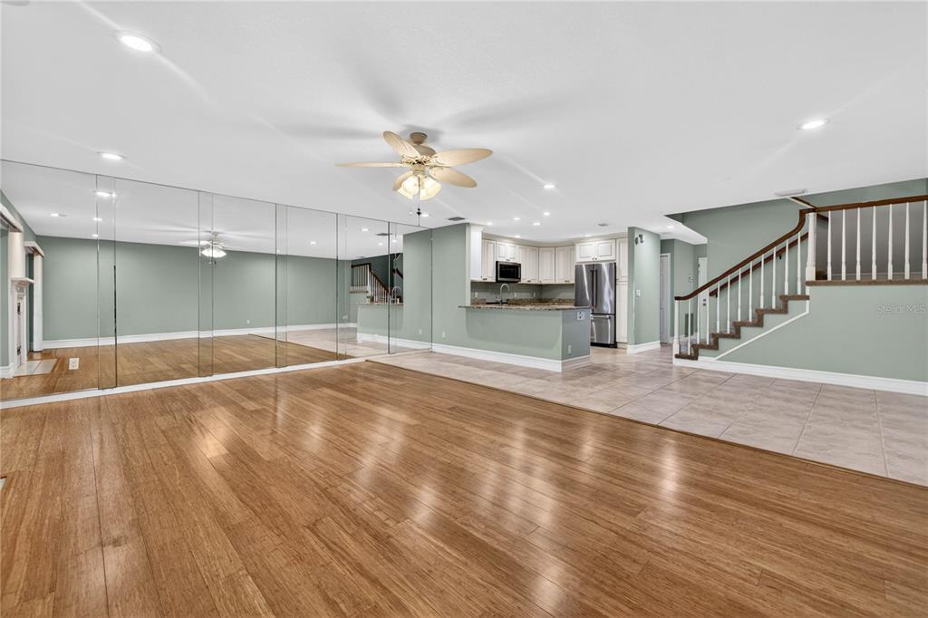 A living room with hardwood floors, a mirrored wall, and an adjacent kitchen and staircase — 9050 PARK BOULEVARD UNIT 7, SEMINOLE, FL