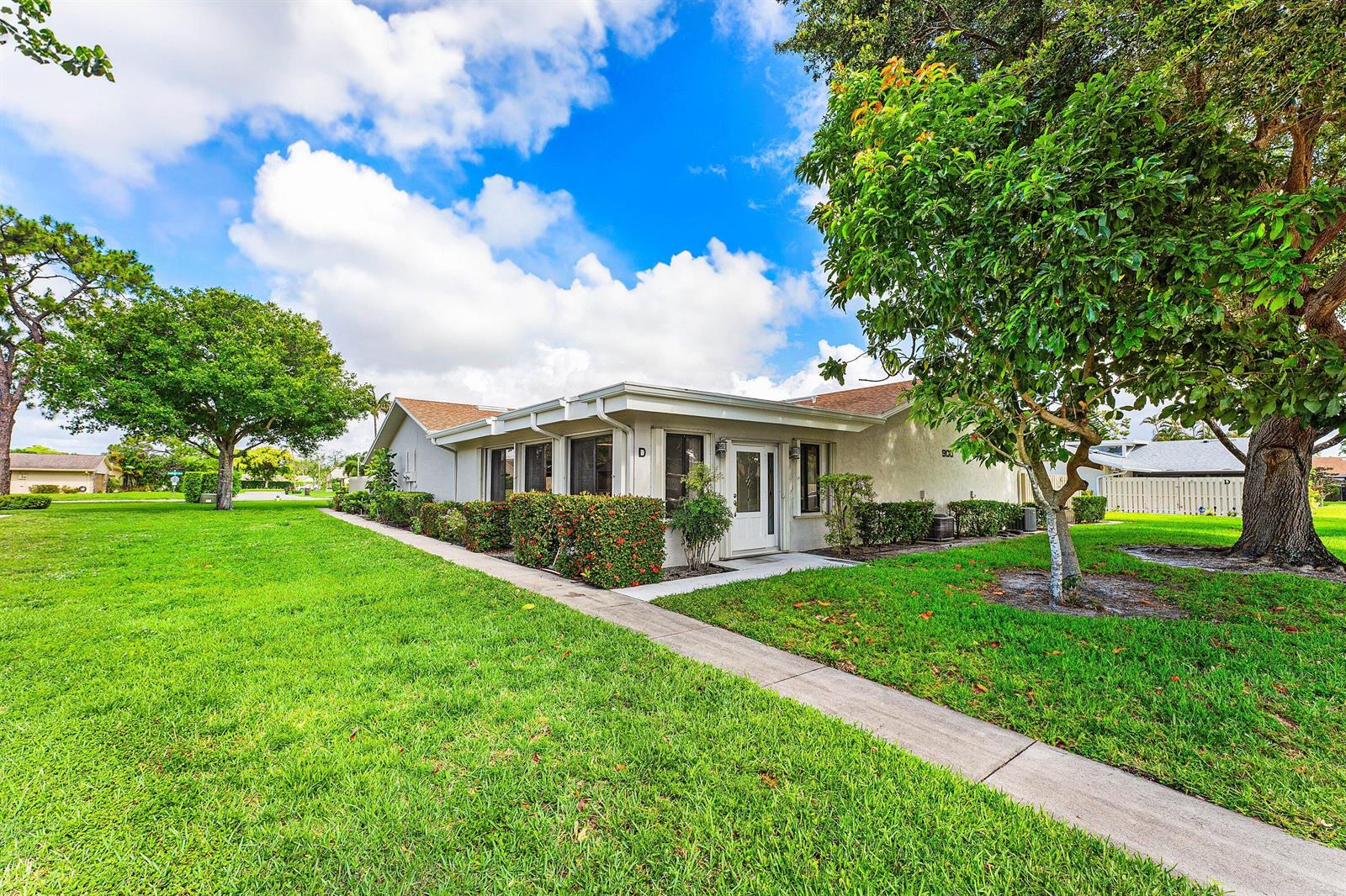A single-story residential building with a white exterior, a front walkway, and surrounding green lawn — 900 NW 30th Avenue # D, Delray Beach FL 33445, DELRAY BEACH, FL