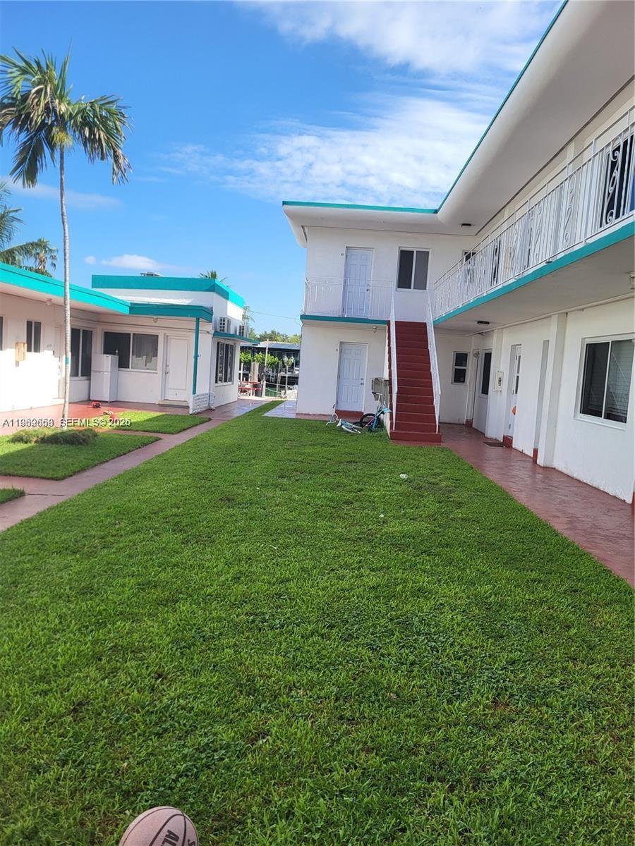 The exterior view shows two white apartment buildings with teal trim and a grassy courtyard — 2101 Calais Dr # 8, Miami Beach FL 33141, MIAMI BEACH, FL