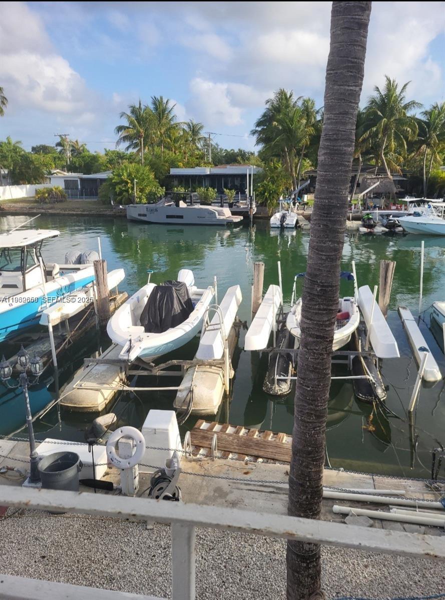 A view of a canal with several boats docked at private lifts and a palm tree — 2101 Calais Dr # 8, Miami Beach FL 33141, MIAMI BEACH, FL