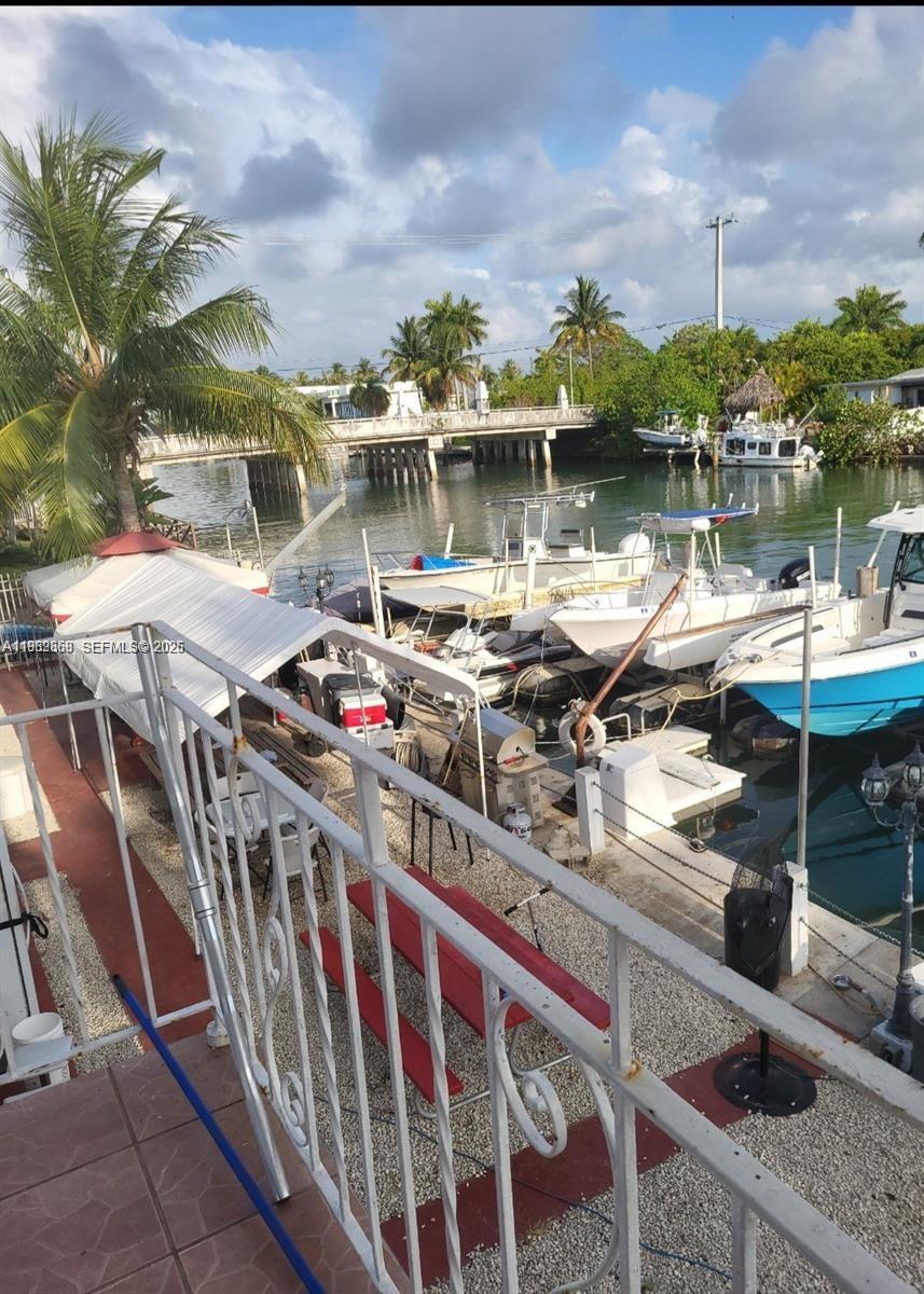 An elevated view shows a patio with a white railing overlooking a canal with boats — 2101 Calais Dr # 8, Miami Beach FL 33141, MIAMI BEACH, FL