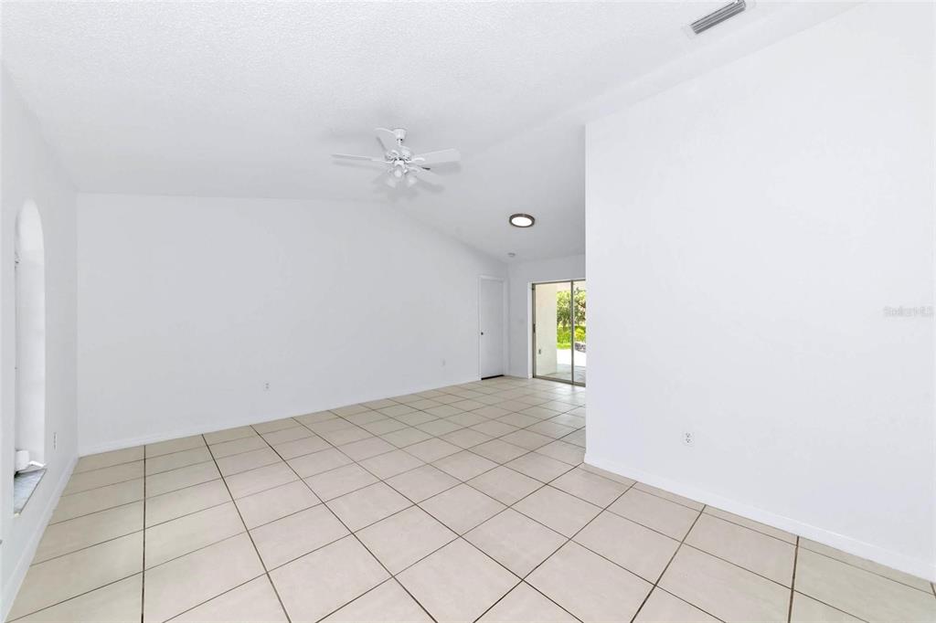 An empty room with white walls, light-colored tile flooring, a ceiling fan, and sliding doors — 4819 WECOMA AVENUE, NORTH PORT, FL