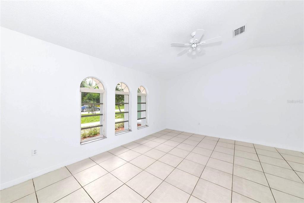 An empty room with white walls, tiled floors, a ceiling fan, and three arched windows — 4819 WECOMA AVENUE, NORTH PORT, FL