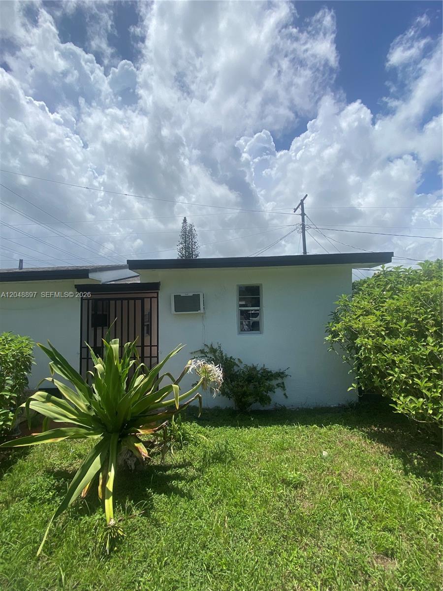 A white exterior wall features a small window, a window air conditioner, and a gated entrance — 15130 Tyler St, Miami FL 33176, MIAMI, FL