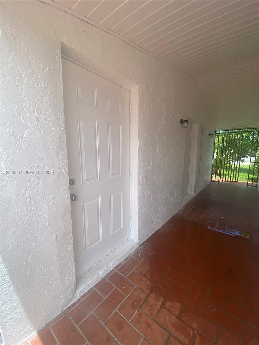 A white door opens onto a covered patio with red brick flooring — 15130 Tyler St, Miami FL 33176, MIAMI, FL