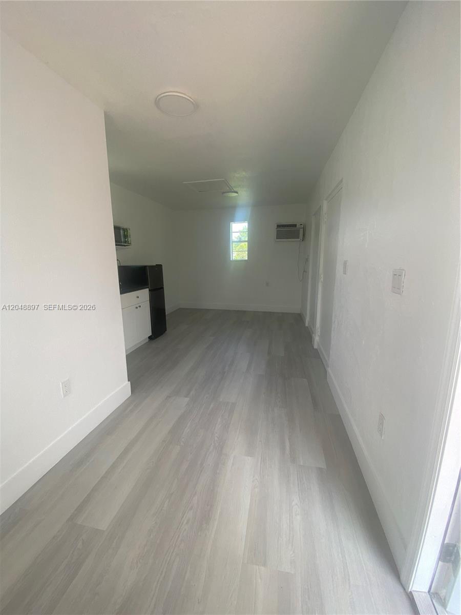 This interior view shows a small studio apartment with light wood-look flooring and a kitchenette — 15130 Tyler St, Miami FL 33176, MIAMI, FL