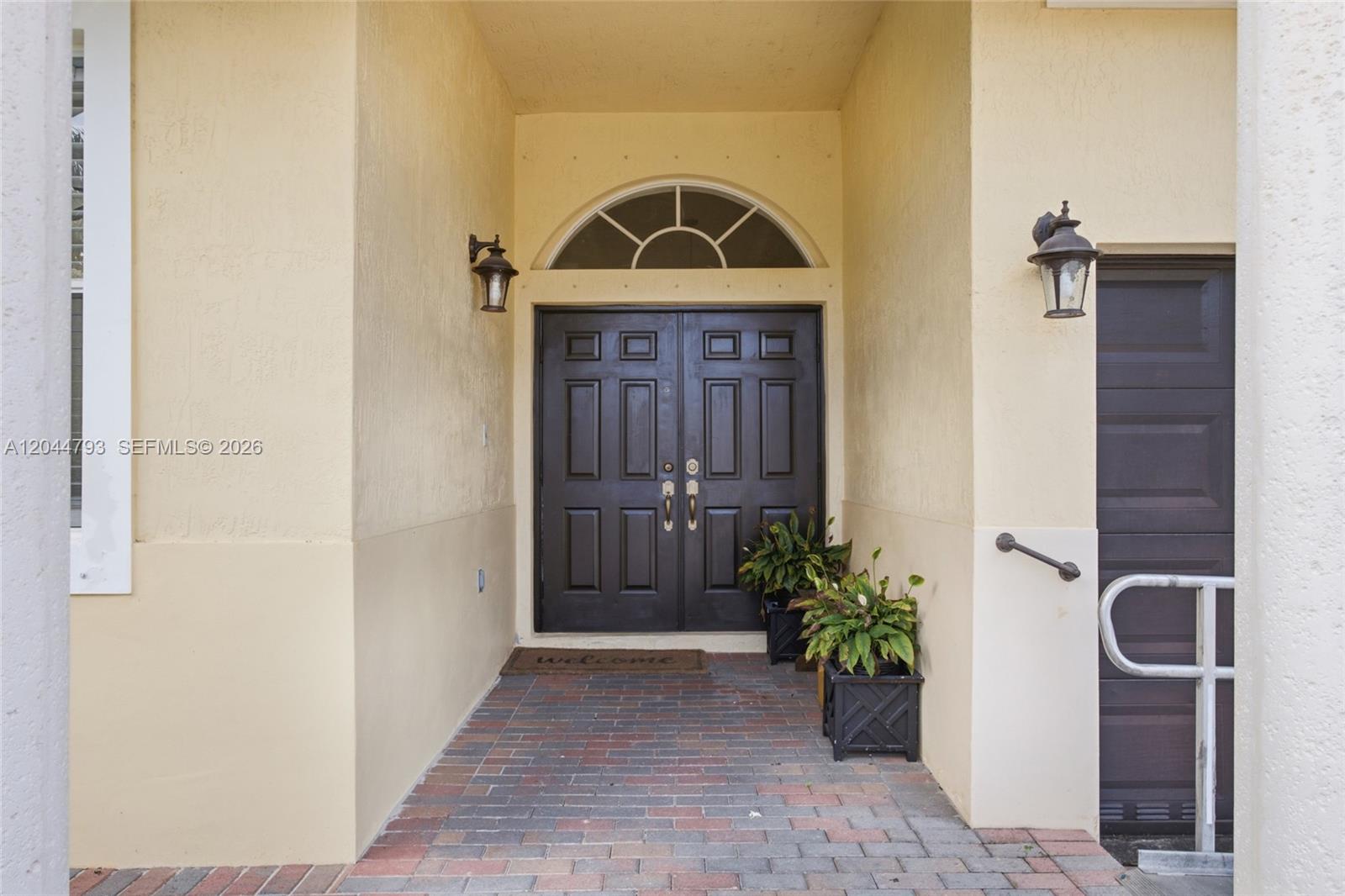 A brick walkway leads to a dark double front door with a transom window — 15125 SW 12th Ter, Miami FL 33194, MIAMI, FL