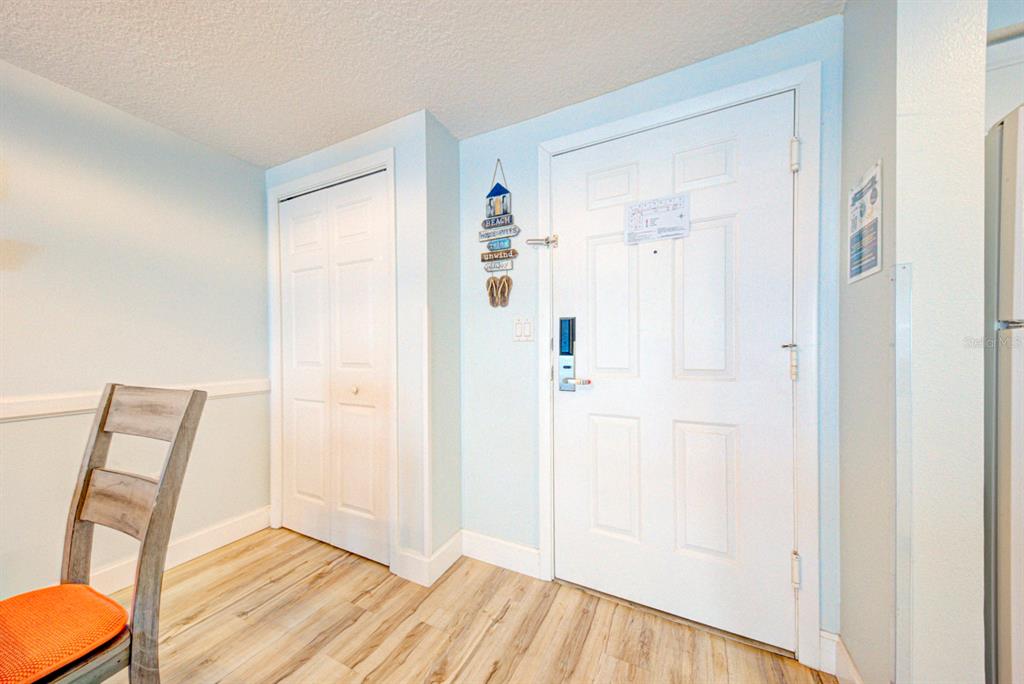 An interior view shows a white door, a closet, and a chair on wood-look flooring — 350 N ATLANTIC AVENUE UNIT 2328, DAYTONA BEACH, FL