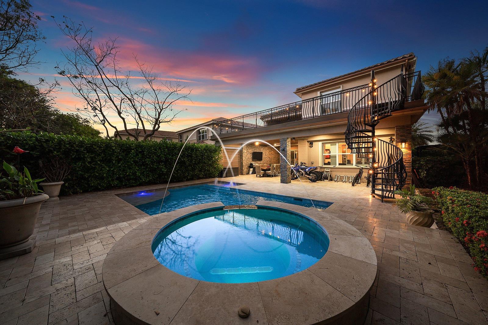 A backyard features a circular spa, a swimming pool with fountains, and a two-story house — 11565 Mantova Bay Circle, Boynton Beach FL 33473, BOYNTON BEACH, FL