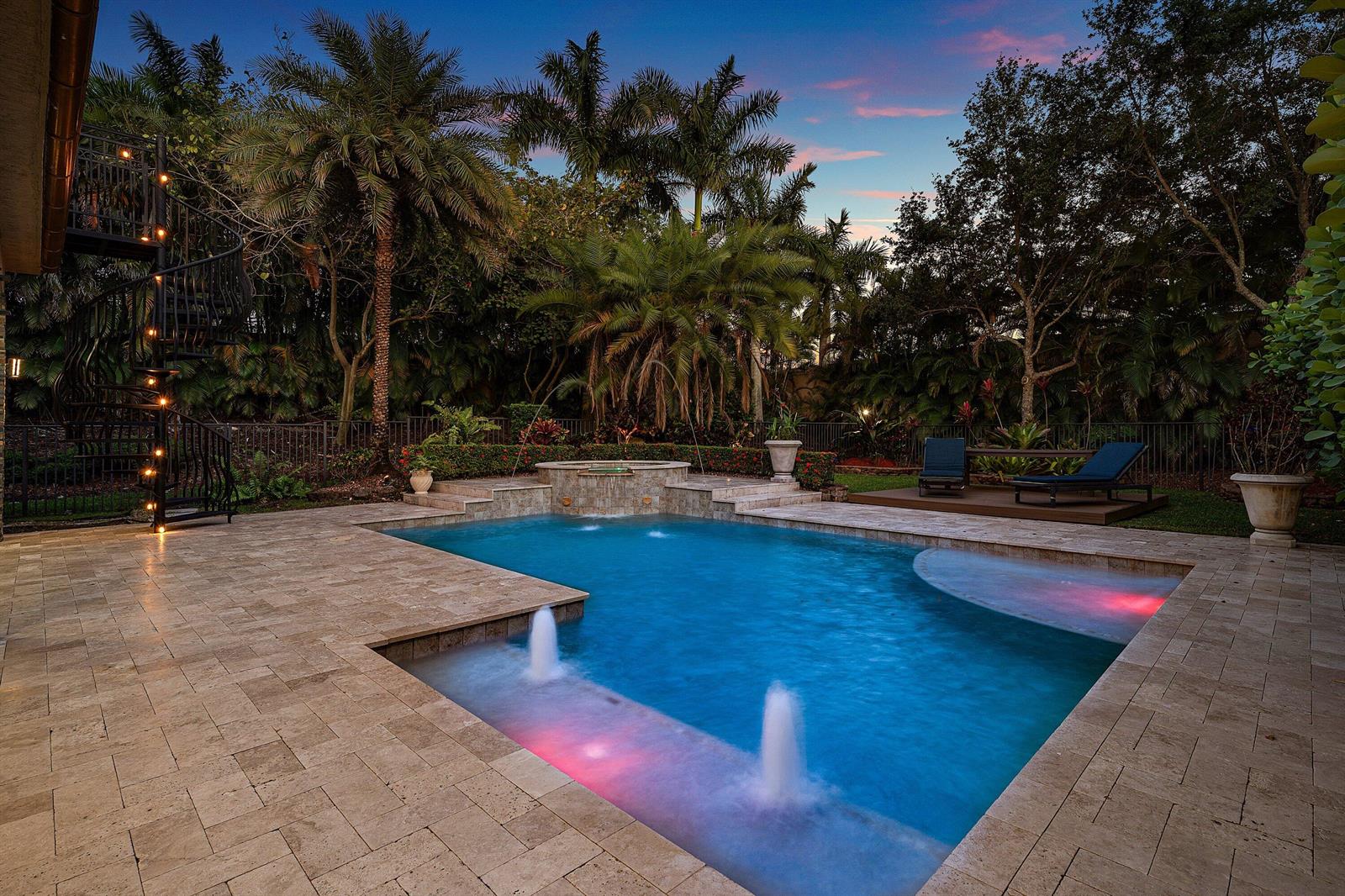 A backyard swimming pool with fountains, a hot tub, and a spiral staircase at dusk — 11565 Mantova Bay Circle, Boynton Beach FL 33473, BOYNTON BEACH, FL