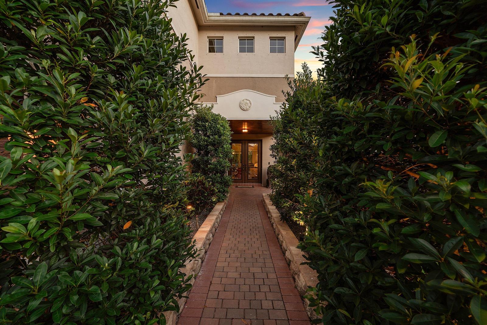 A brick walkway leads through tall hedges to the front entrance of a two-story home — 11565 Mantova Bay Circle, Boynton Beach FL 33473, BOYNTON BEACH, FL