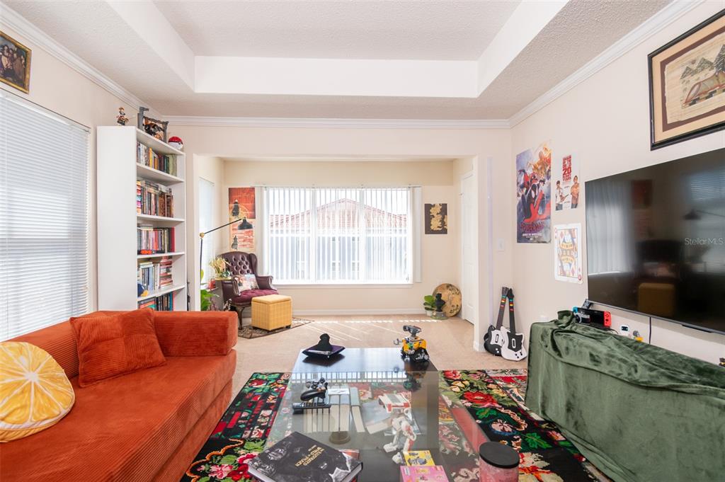 A living room features an orange sofa, a glass coffee table, and a large television — 18001 RICHMOND PLACE DRIVE UNIT 1137, TAMPA, FL