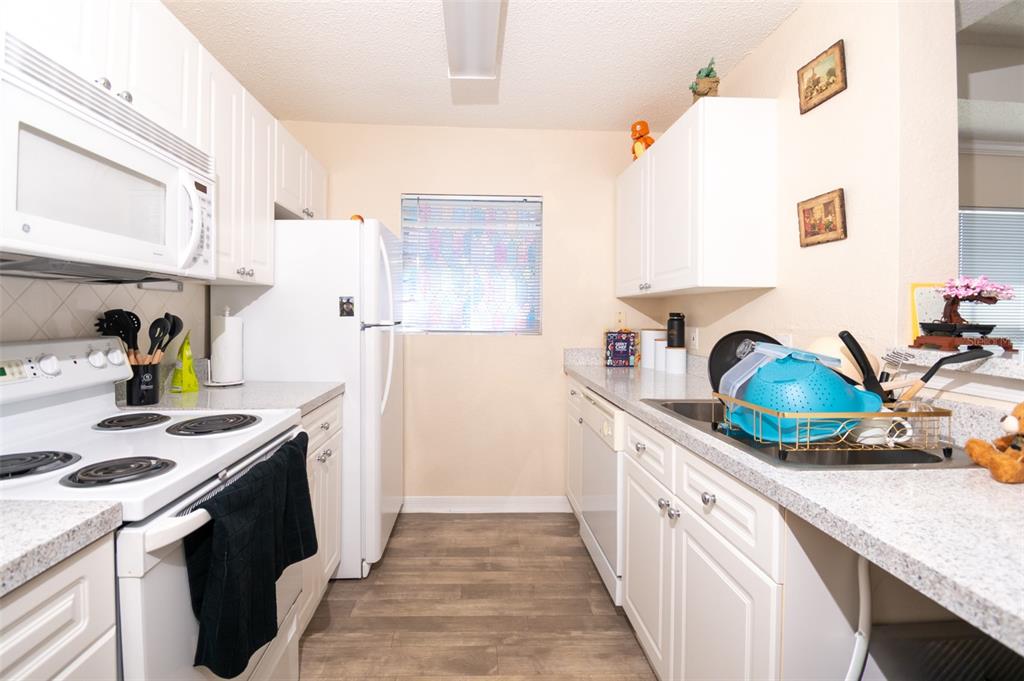 A galley kitchen features white cabinets, light countertops, a white stove, and a white refrigerator — 18001 RICHMOND PLACE DRIVE UNIT 1137, TAMPA, FL
