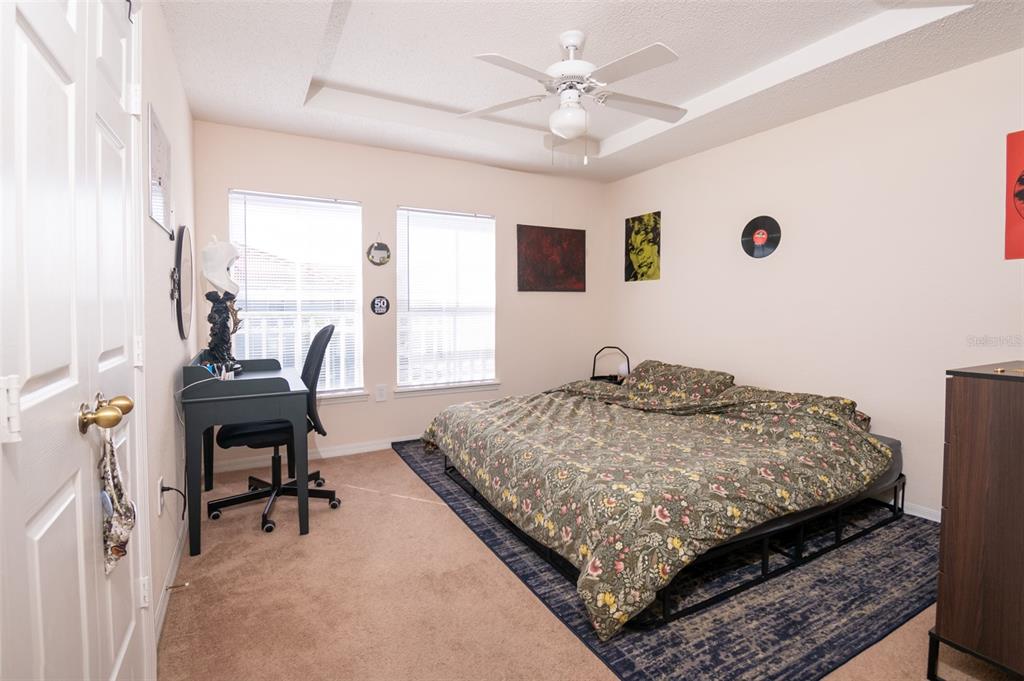 A bedroom features a bed with a floral comforter, a desk, and a ceiling fan — 18001 RICHMOND PLACE DRIVE UNIT 1137, TAMPA, FL