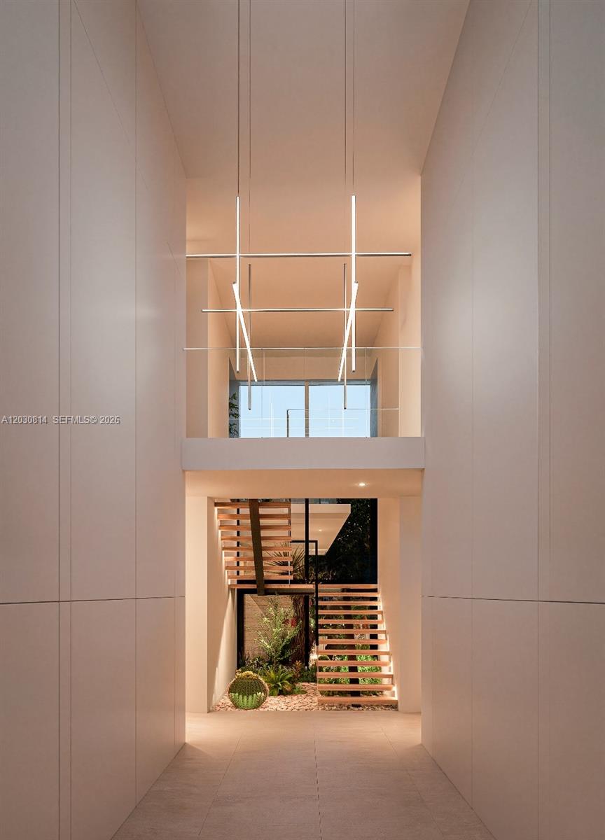 A minimalist hallway features a floating wooden staircase and a modern geometric pendant light fixture — 6100 W Suburban Dr, Pinecrest FL 33156, PINECREST, FL