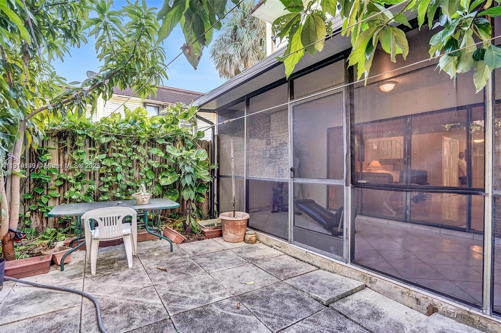 A patio with a table and chair sits outside a screened-in porch with tiled flooring — 2701 N 34th Ave # 1D, Hollywood FL 33021, HOLLYWOOD, FL