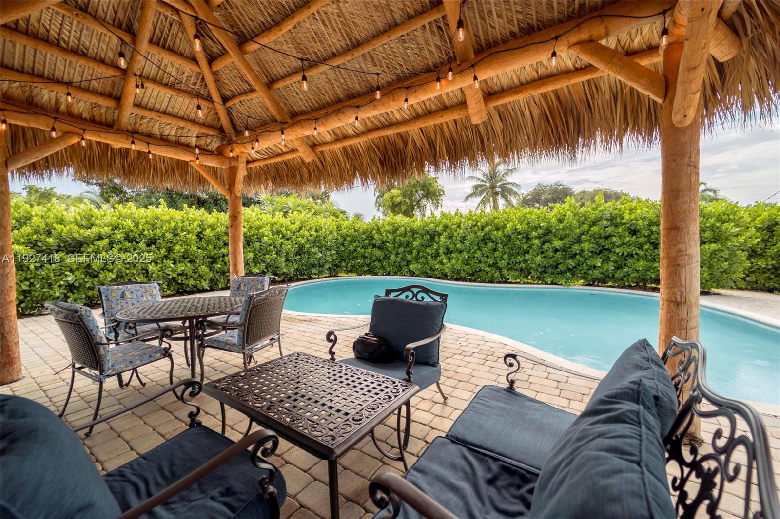 A thatched-roof tiki hut overlooks a swimming pool surrounded by a hedge — 269 SE 8th Ave, Deerfield Beach FL 33441, DEERFIELD BEACH, FL