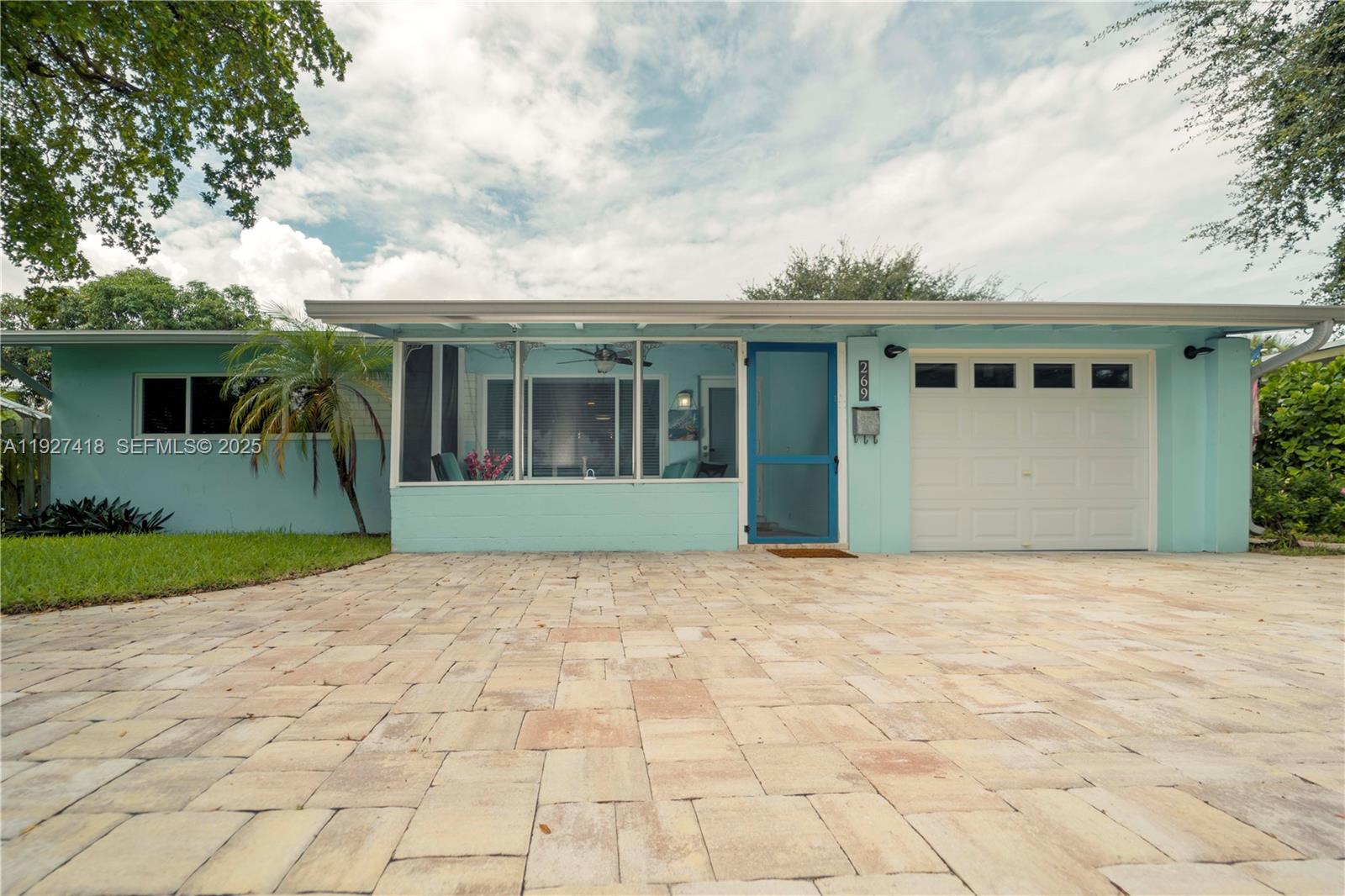 A light blue single-story house features a screened-in porch, a garage, and a paved driveway — 269 SE 8th Ave, Deerfield Beach FL 33441, DEERFIELD BEACH, FL