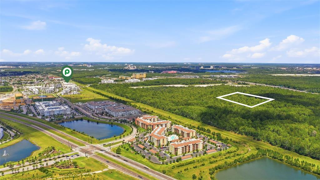 An aerial view shows a large, undeveloped plot of land outlined in white near apartments — S APOPKA VINELAND ROAD, ORLANDO, FL