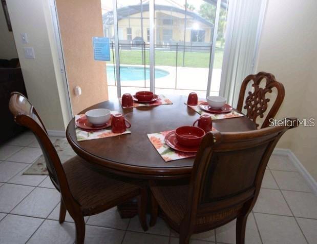 A round wooden dining table with four chairs sits in front of a sliding glass door — 137 ROSSO DRIVE, DAVENPORT, FL