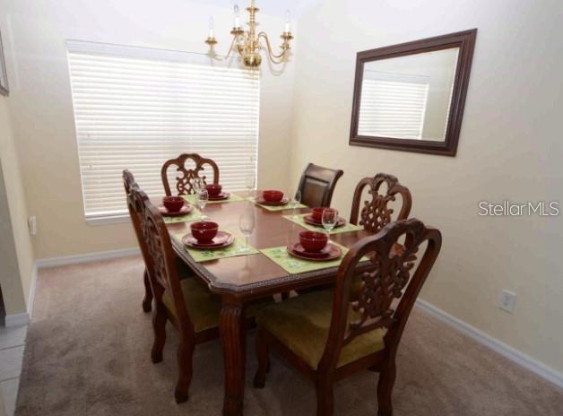 A dining room features a wooden table with six chairs, a chandelier, and a wall mirror — 137 ROSSO DRIVE, DAVENPORT, FL