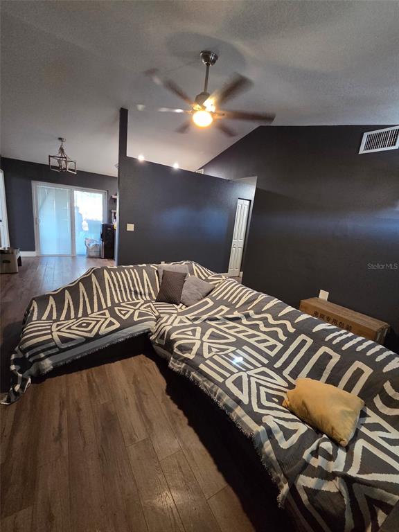 A living room features dark walls, wood-look flooring, a ceiling fan, and a sectional sofa — 3101 SEVEN SPRINGS BOULEVARD, NEW PORT RICHEY, FL