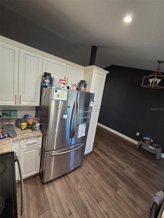 A kitchen features white cabinets, stainless steel appliances, and dark walls with wood-look flooring — 3101 SEVEN SPRINGS BOULEVARD, NEW PORT RICHEY, FL