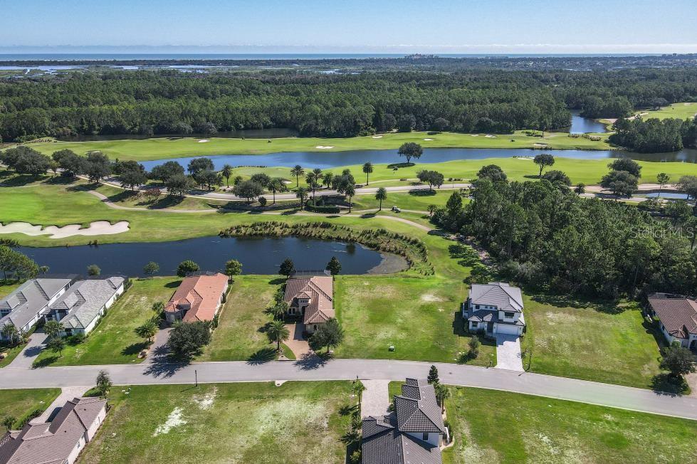 An aerial view shows several houses situated along a golf course with ponds and distant water — 339 HIBISCUS WAY, PALM COAST, FL