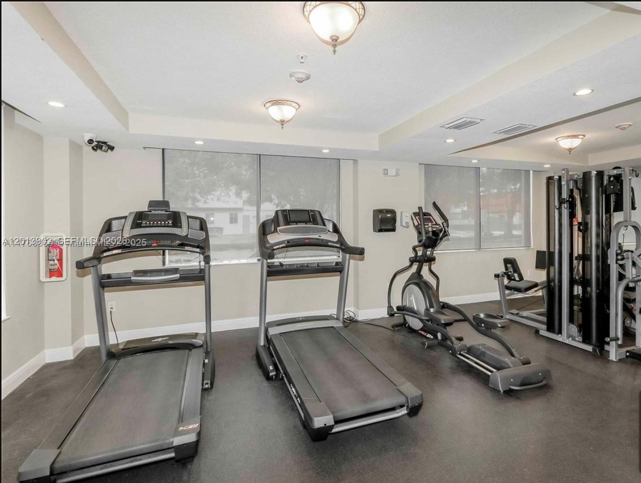 A gym room features two treadmills, an elliptical machine, and a multi-station weight machine — 3590 Coral Way # 910, Miami FL 33145, MIAMI, FL