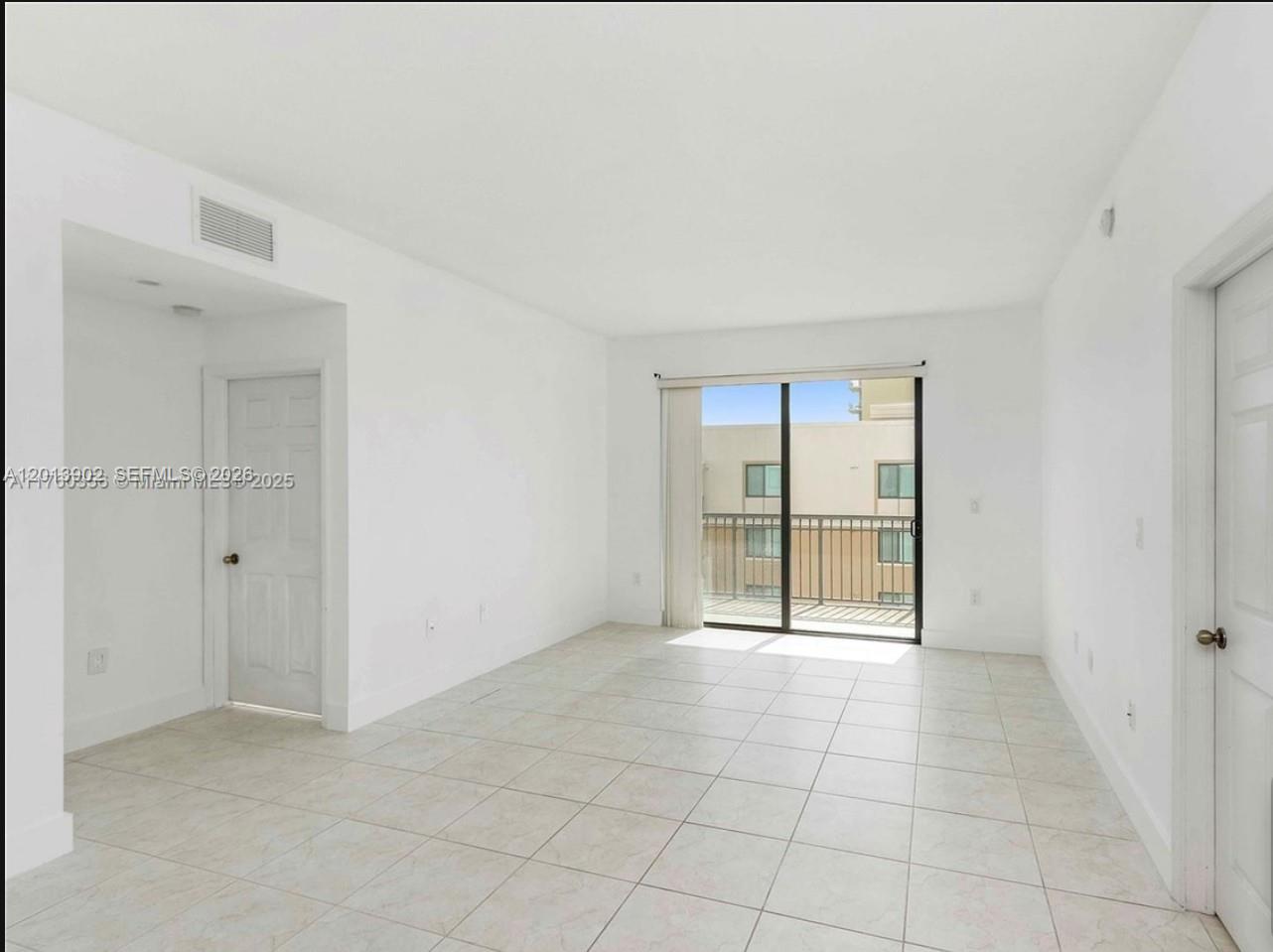 An empty room with white walls, tile flooring, a sliding glass door, and a balcony — 3590 Coral Way # 910, Miami FL 33145, MIAMI, FL
