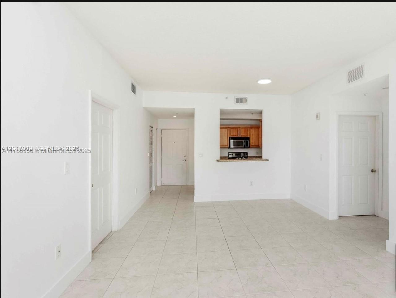 An empty room with white walls, tile flooring, and a pass-through window to the kitchen — 3590 Coral Way # 910, Miami FL 33145, MIAMI, FL