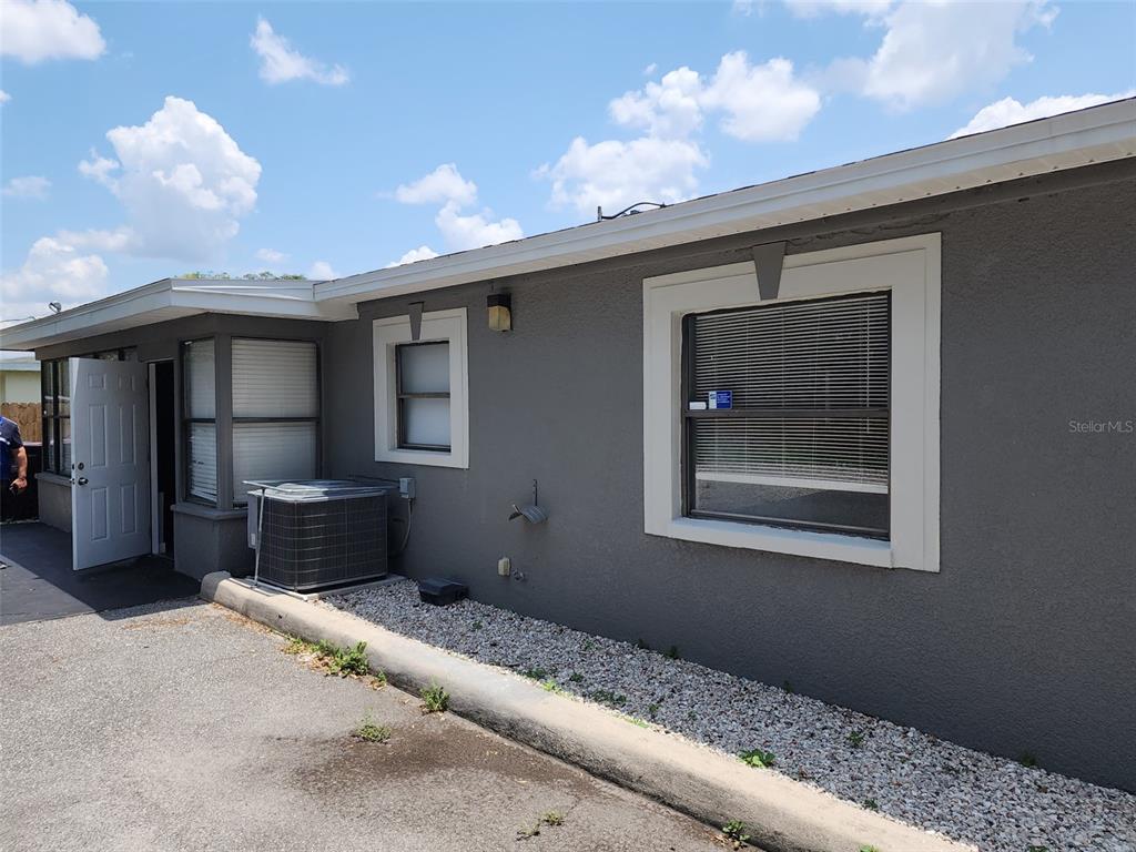 A gray exterior wall features two windows, an open door, and an outdoor HVAC unit — 60 S SEMORAN BOULEVARD, ORLANDO, FL