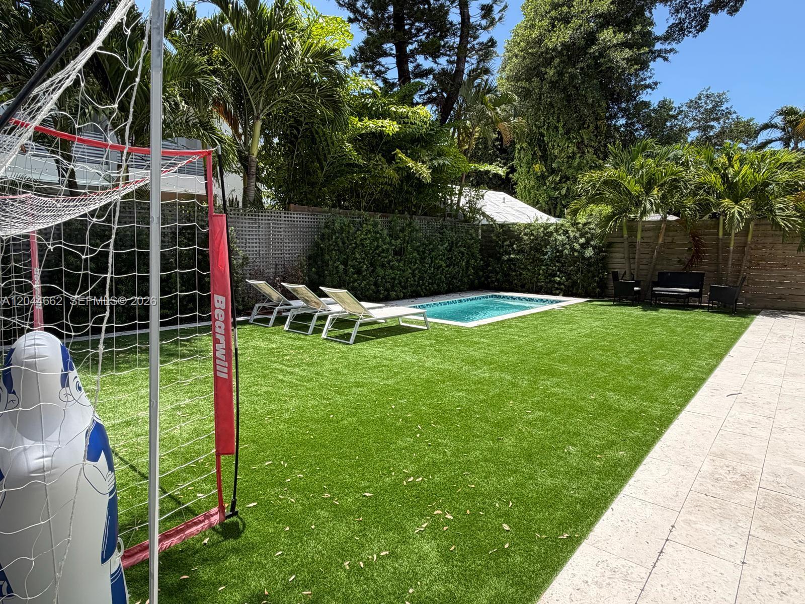 A backyard features a small swimming pool, lounge chairs, and a soccer goal on turf — 2401 SW 16th Ct, Miami FL 33145, MIAMI, FL