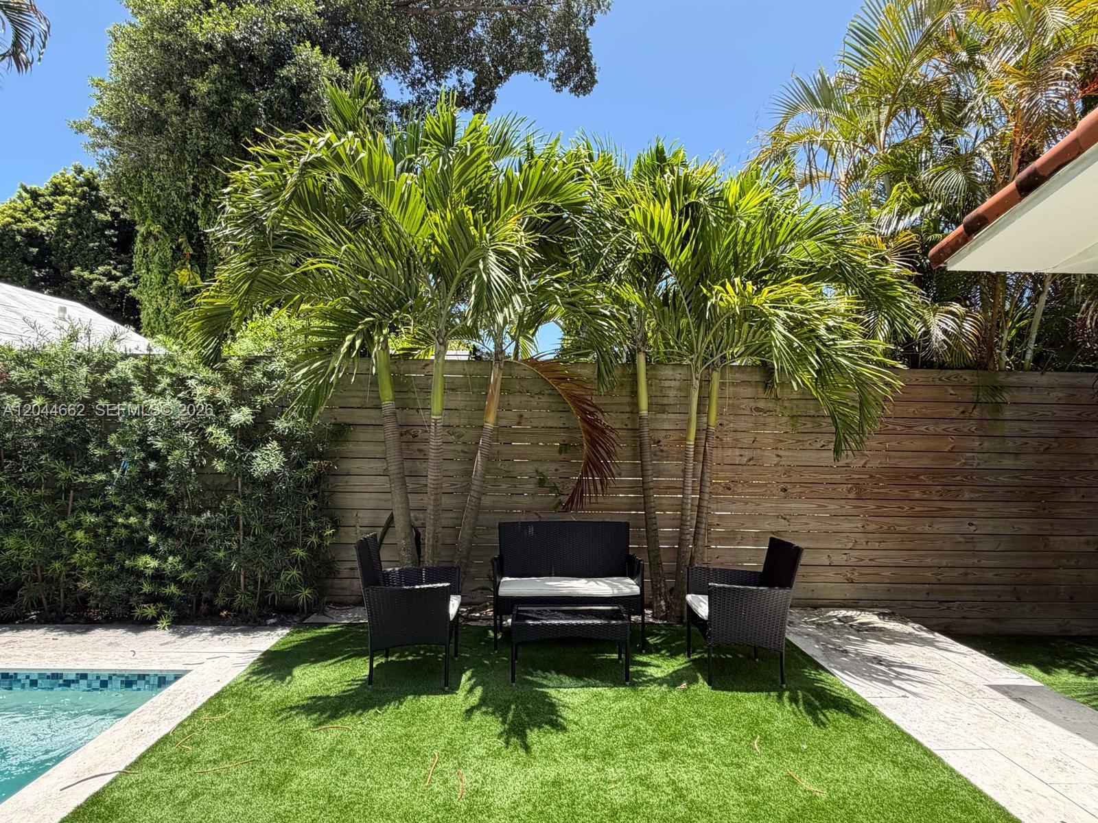 A patio area features a black wicker furniture set on artificial turf beside a pool — 2401 SW 16th Ct, Miami FL 33145, MIAMI, FL