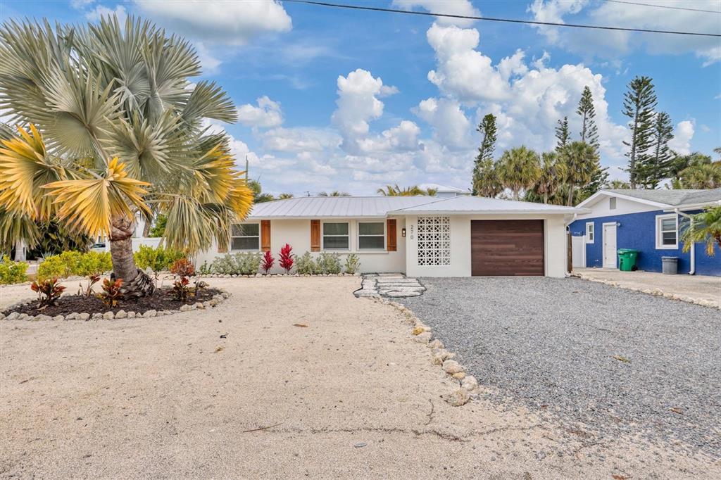 A single-story house with a gravel driveway, a palm tree, and a metal roof — 270 GLADIOLUS STREET, ANNA MARIA, FL