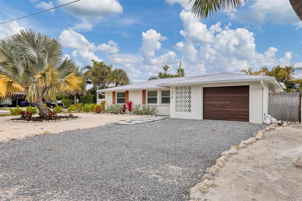 A single-story house with a gravel driveway, a metal roof, and decorative breeze block accents — 270 GLADIOLUS STREET, ANNA MARIA, FL