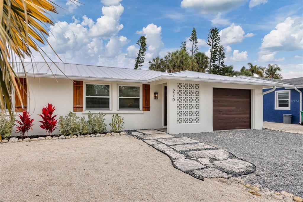 A white single-story house features a metal roof, a breeze block wall, and a driveway — 270 GLADIOLUS STREET, ANNA MARIA, FL