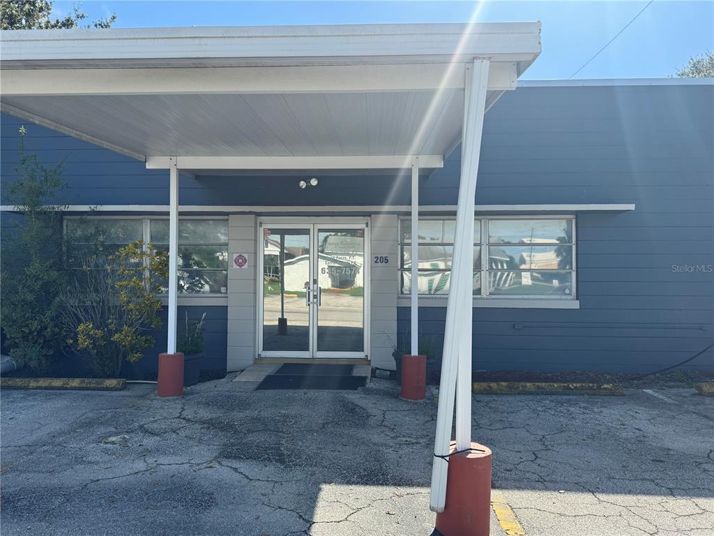 The exterior of a single-story commercial building features a covered entrance with a glass door — 205 N SCENIC HIGHWAY, FROSTPROOF, FL